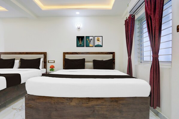 A hotel room with two beds, a small table with a vase, and artwork on the wall. - Hotel O Aqua Comforts (Bangalore)