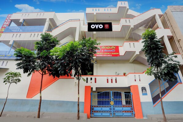A building with multiple balconies, a blue gate, and signage indicating 'ROOMS AVAILABLE'.