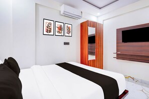 Un dormitorio moderno con cama, armario, televisor empotrado y cuadros enmarcados.