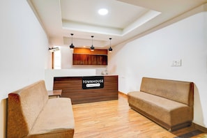 A reception area with a sign indicating it's a company-serviced townhouse. There are two sofas and a wooden reception desk. - Power Break Townhouse Whitefield (Bangalore)