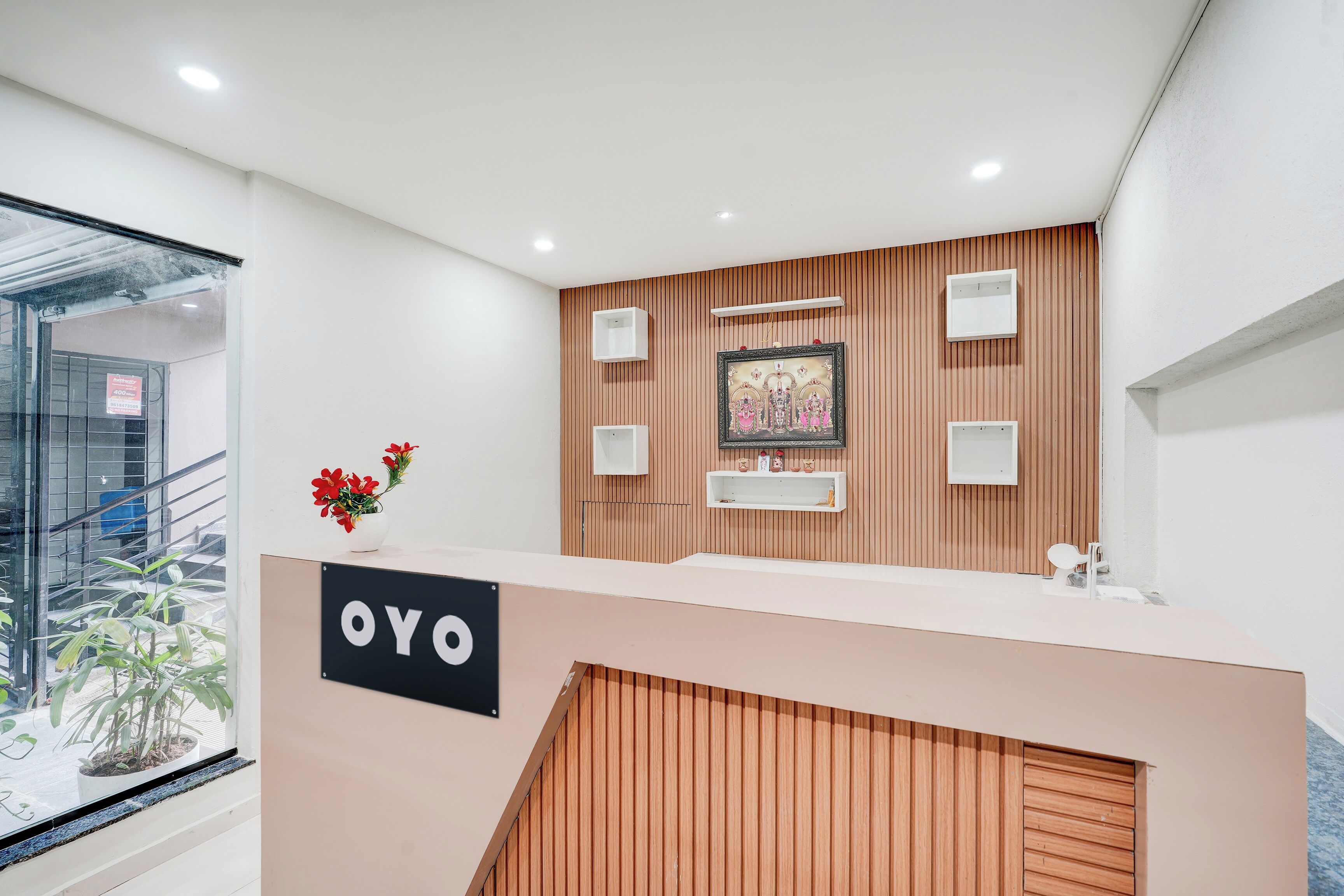 A reception desk with a wooden panel wall, a framed artwork, and a sign that reads 'OYO'.