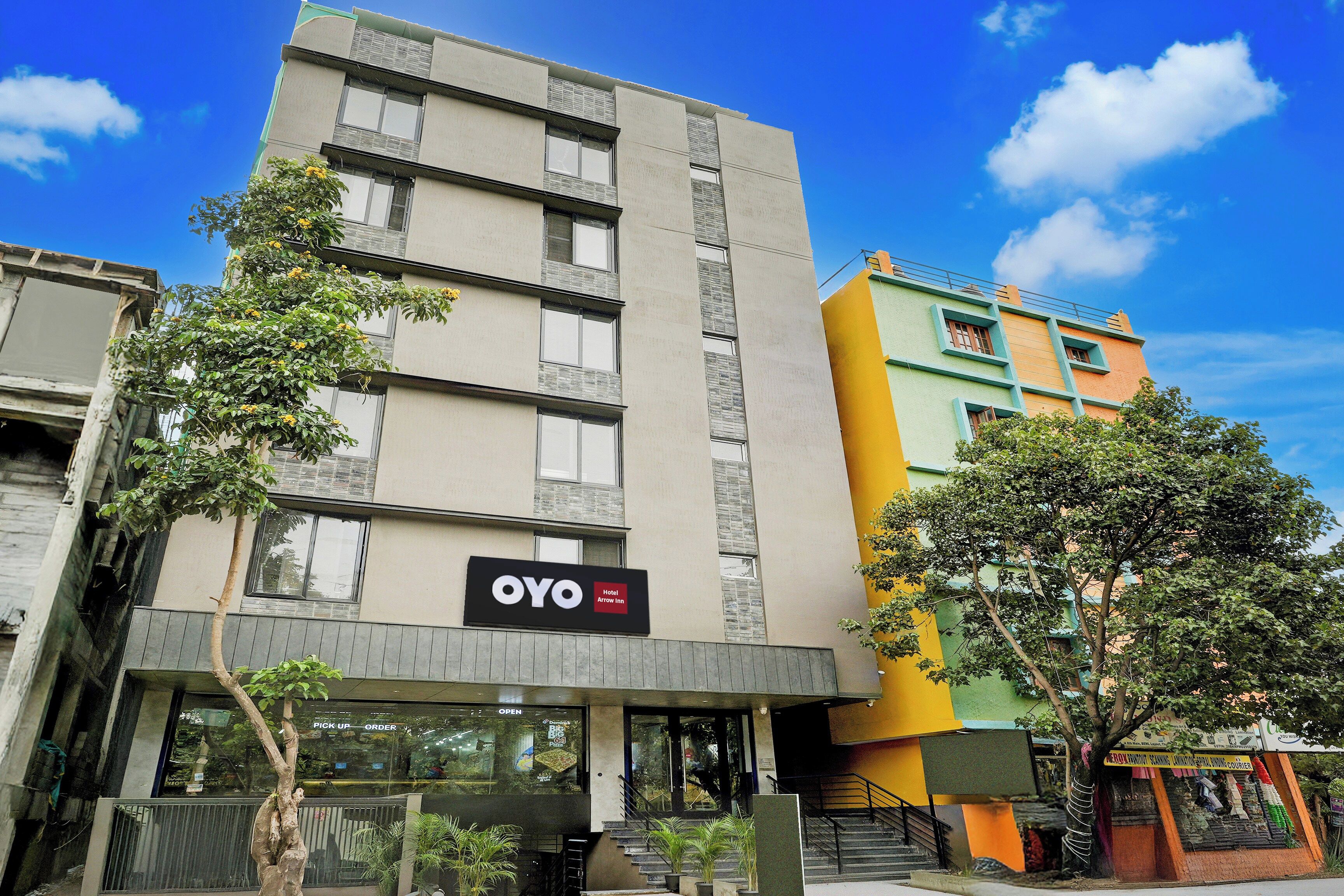 A hotel building with a sign for OYO Hotel Arrow Inn, featuring a modern facade with multiple windows and a visible entrance.