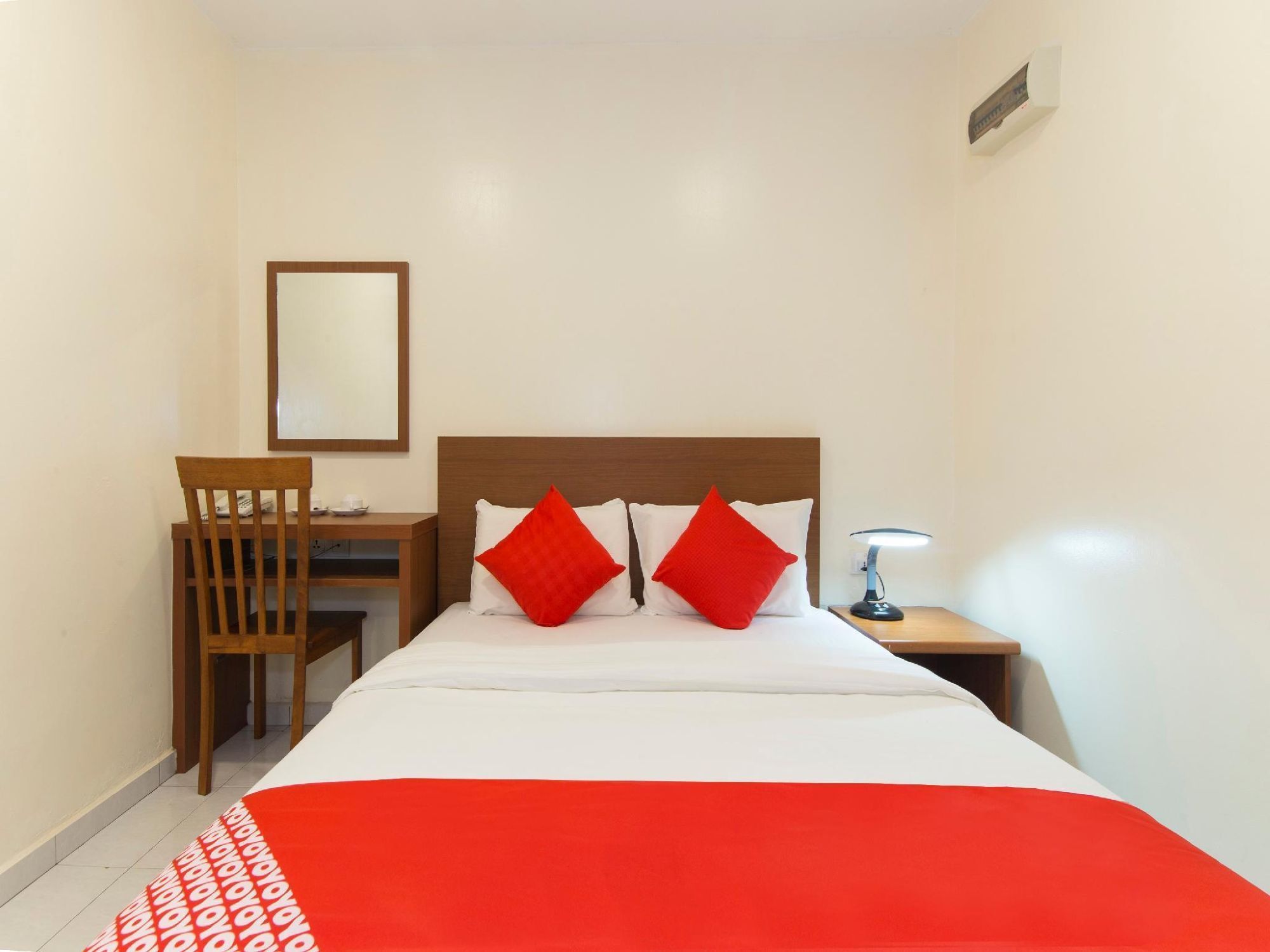 Ein Hotelzimmer mit Bett, Schreibtisch, Stuhl, Nachttisch und Spiegel.
