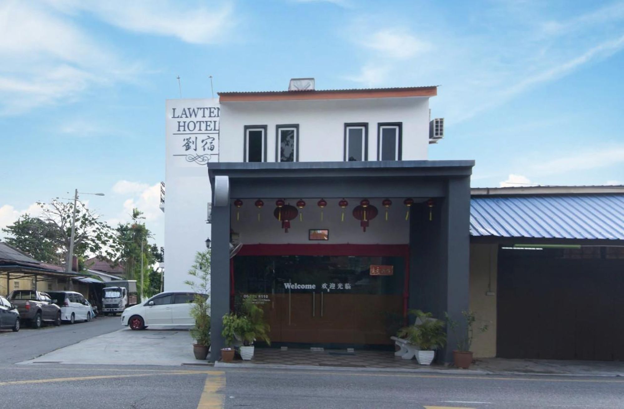 A hotel entrance with a sign reading 'LAWTER HOTEL' and a welcome sign in a foreign language.