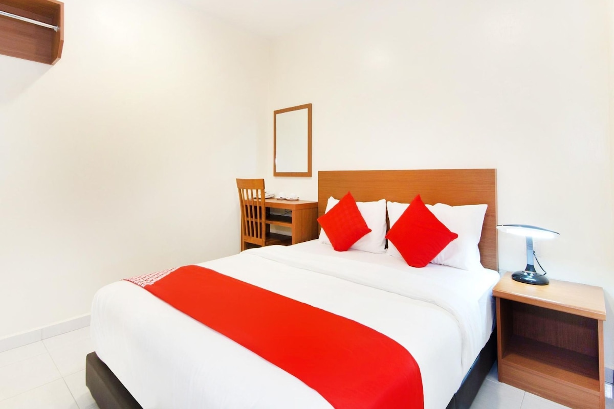 A hotel room with a bed, a nightstand, a desk, and a chair.