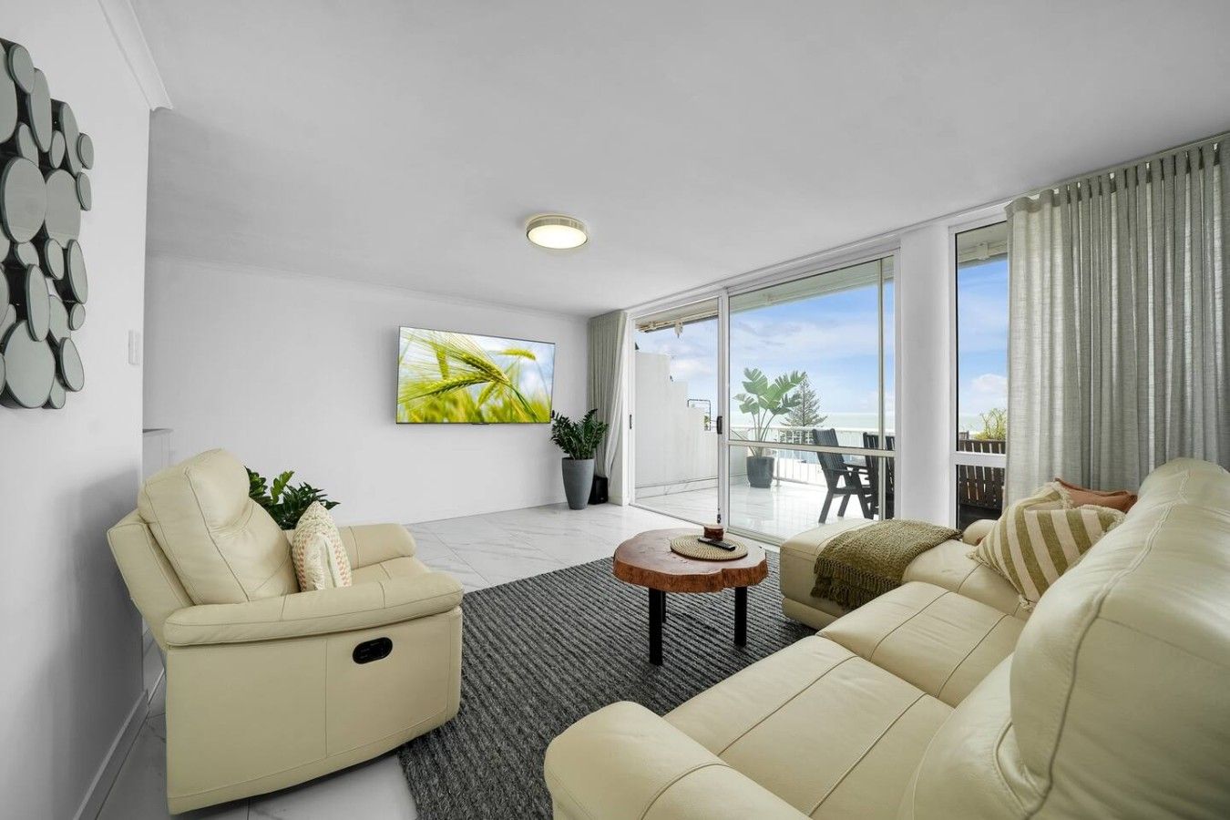 A modern living room with a sofa, a coffee table, and a TV mounted on the wall.