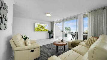 A modern living room with a sofa, a coffee table, and a TV mounted on the wall.