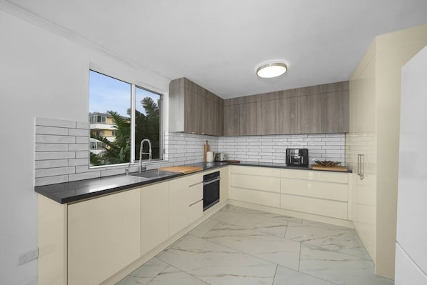 Een moderne keuken met een groot raam, witte metrotegels en een marmeren vloer.