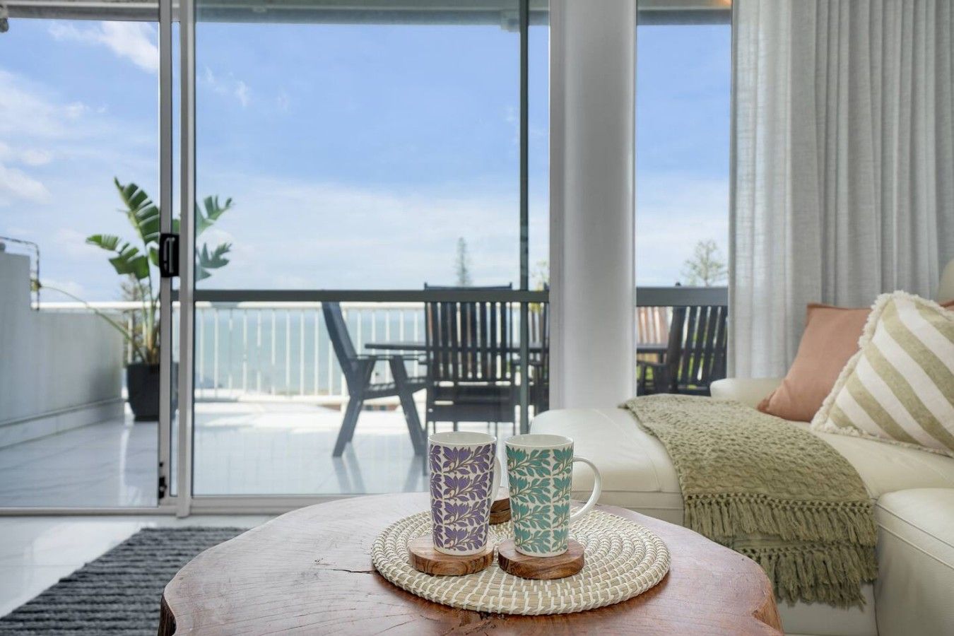 Een balkon met uitzicht, een zithoek met een tafel en twee decoratieve vazen.
