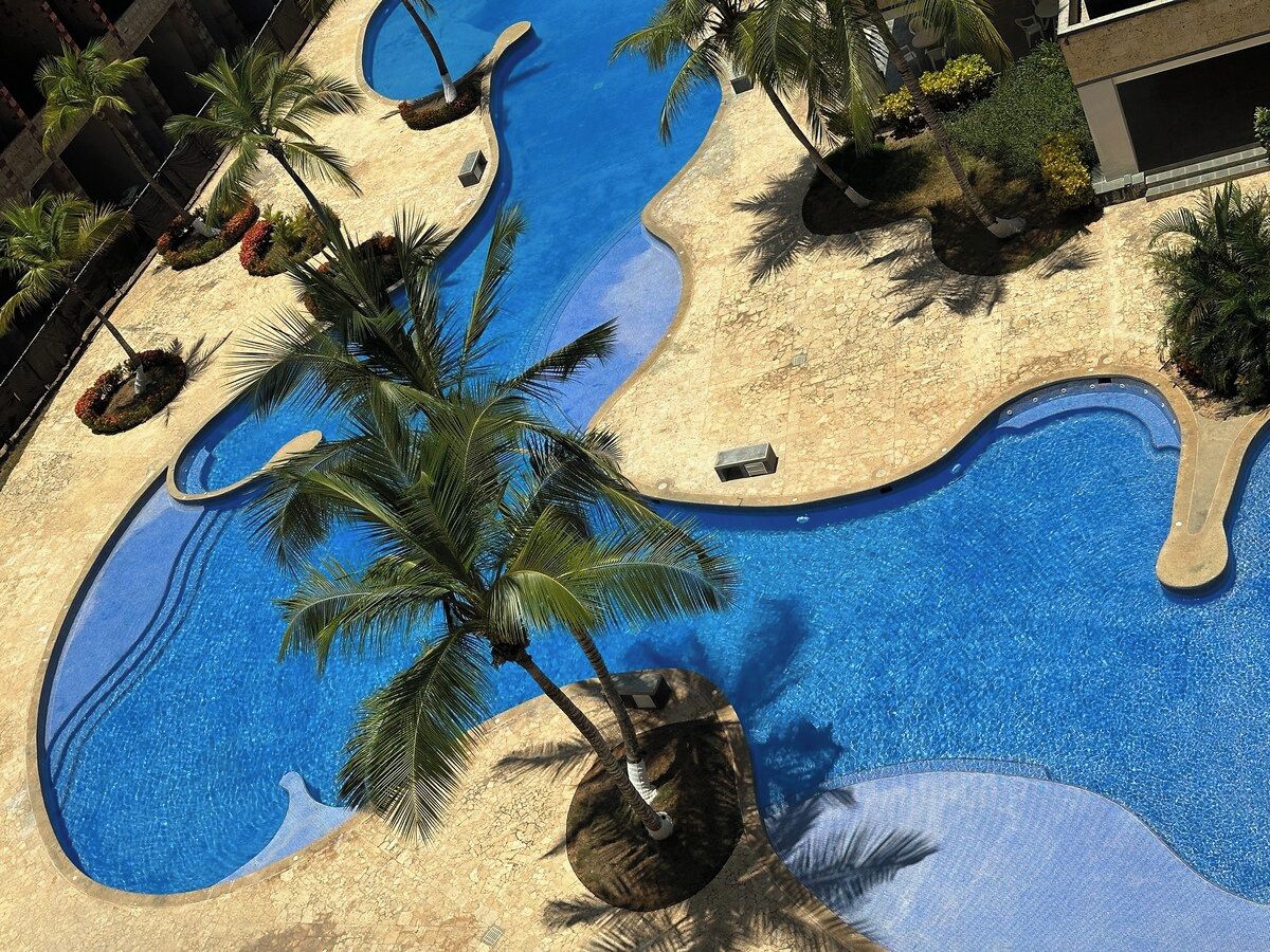 A swimming pool with a unique design, surrounded by palm trees and plants.