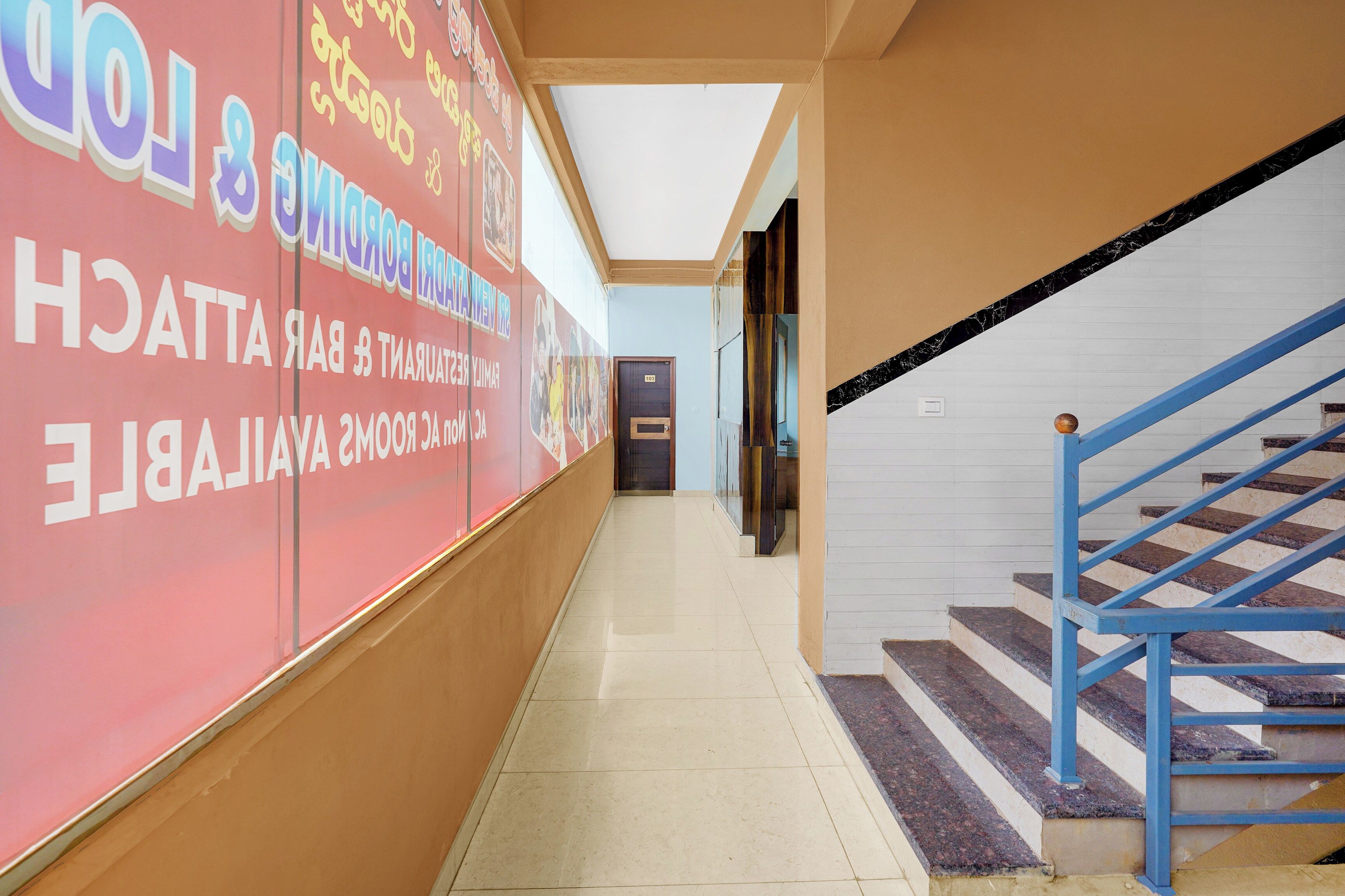Un couloir avec un escalier sur la droite, une porte au fond et un mur orné de textes et d’images.
