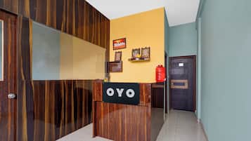 En receptionsdisk med et skilt, der viser 'OYO', i en moderne bygning med træpaneler og flisegulv.