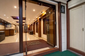 Un vestíbulo de hotel con mostrador de recepción, zona de estar y entrada con puerta de vidrio.
