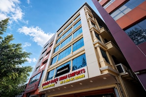 Un edificio de varios pisos con un letrero que dice 'INDIAN COMFORTS A/C & NON A/C ROOMS'.
