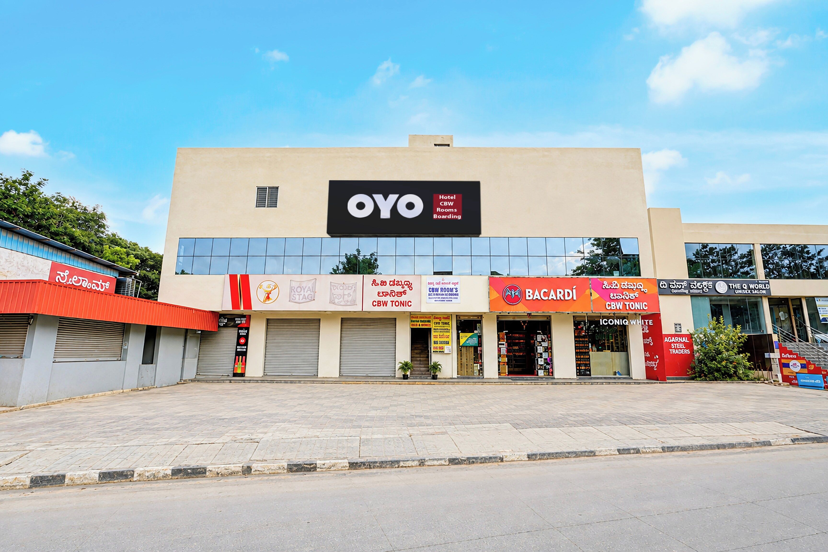 A hotel with a sign reading 'OYO Hotel CBW Rooms Boarding' and various other signs for local businesses.