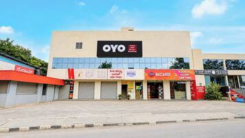 A hotel with a sign reading 'OYO Hotel CBW Rooms Boarding' and various other signs for local businesses.