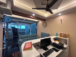 A modern office space with a desk, computer, and a blue sofa. - Hotel O Srinidhi Inn (Bangalore)
