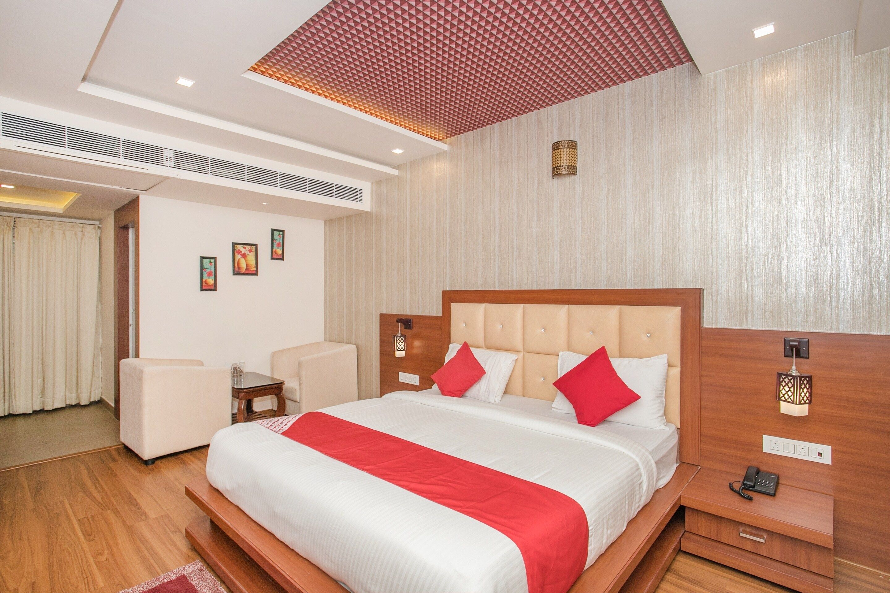 Habitación de hotel con una cama grande, una mesita de noche con un teléfono, una pequeña mesa con una lámpara y una silla.