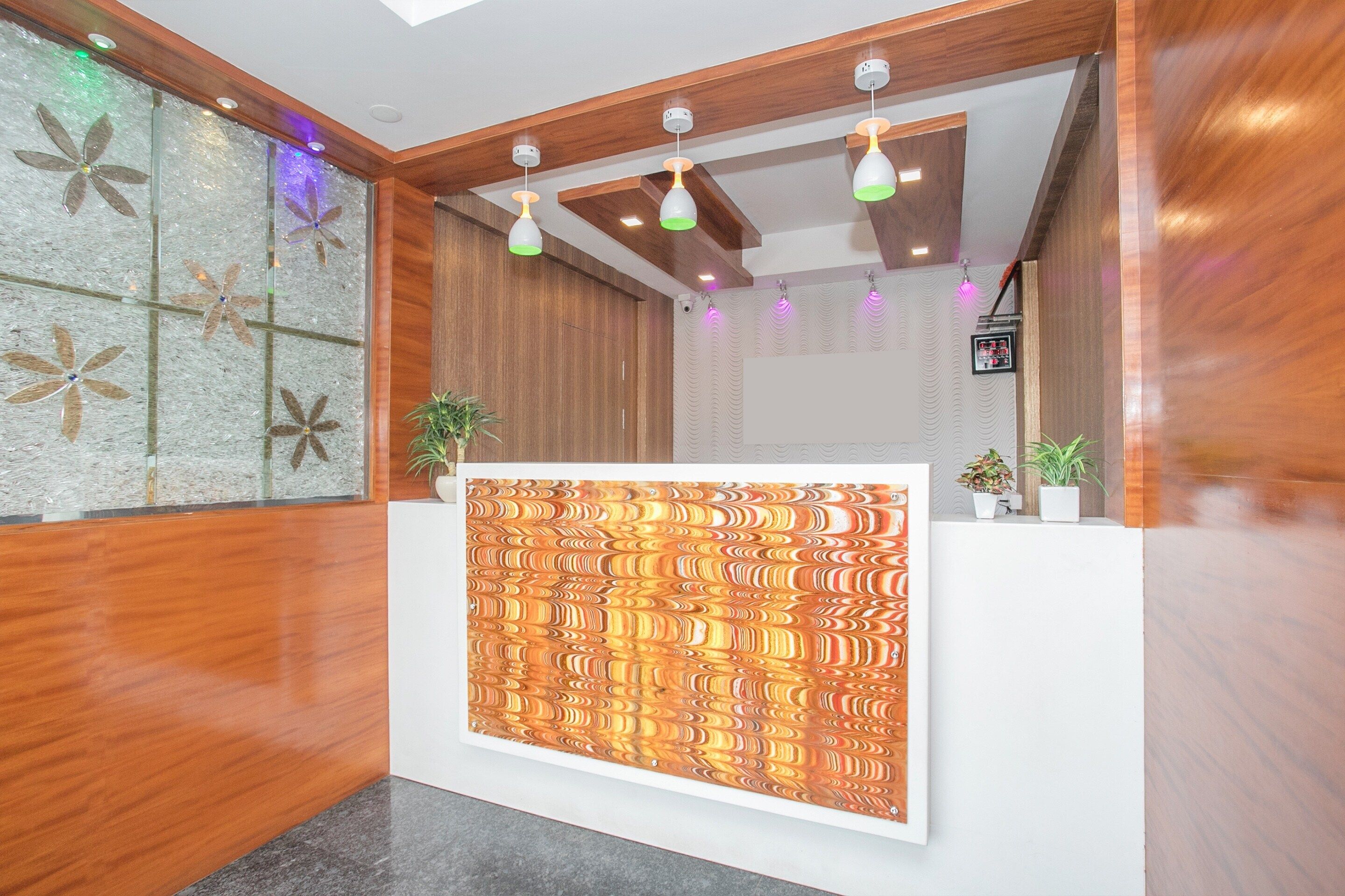 Zona de recepción con un mostrador de madera, pared con diseño y luminarias en el techo.