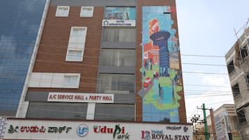 A building with a service hall and party hall on the ground floor, a mural on the side, and multiple signs for businesses including a hotel.