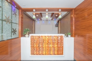 Taulell de recepció amb un fons decoratiu, revestiment de fusta a les parets i il·luminació penjant del sostre.