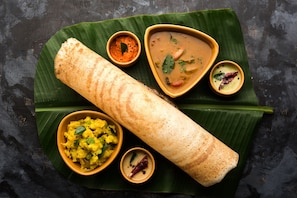 A traditional South Indian meal with a dosa, sambar, and coconut chutney on a banana leaf. - Hotel O Petunia Boutique Hotel (Bangalore)