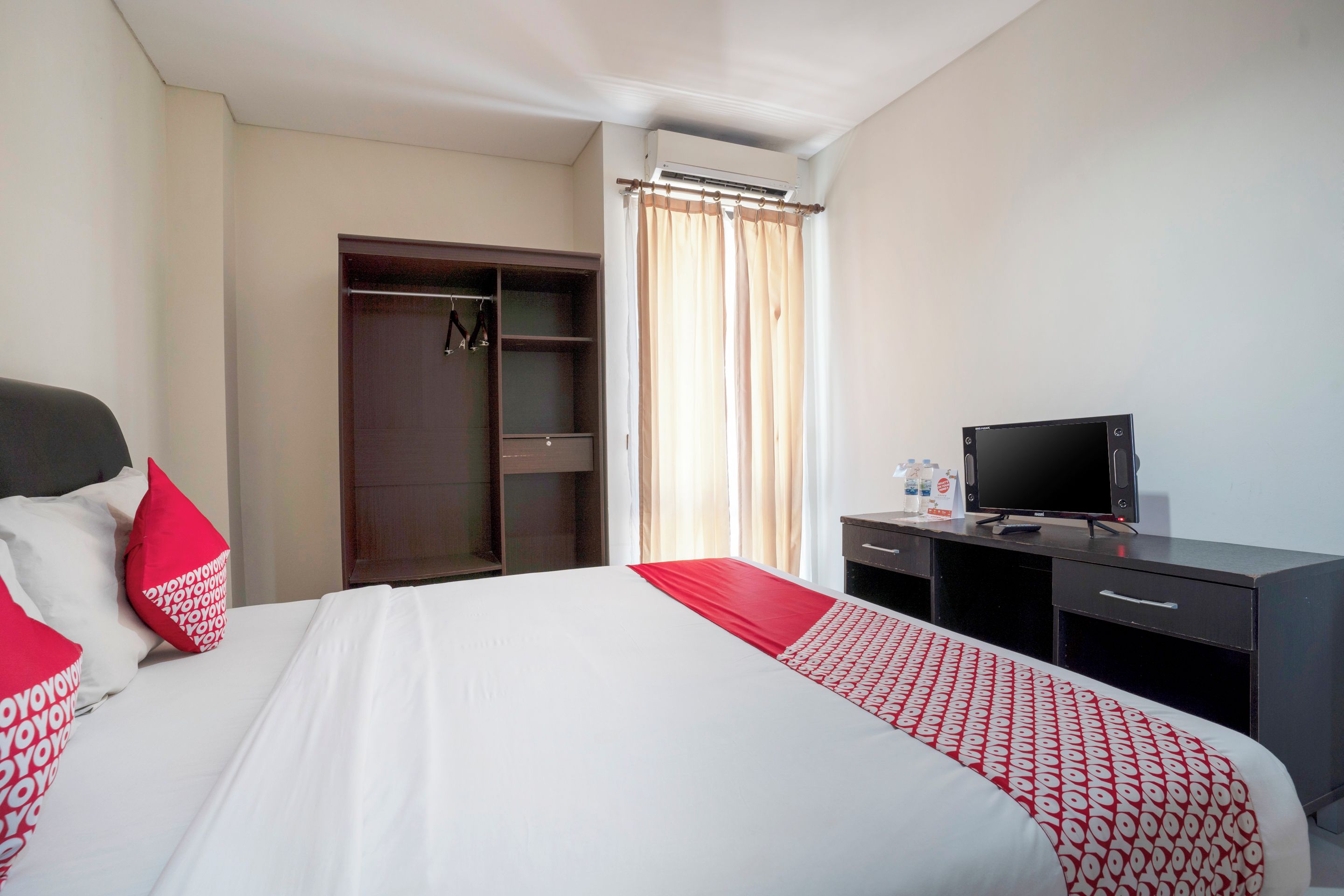 A hotel room with a bed, a desk, a television, and a wardrobe.