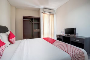 A hotel room with a bed, a desk, a television, and a wardrobe. - Hotel O Near Airport Ngurah Rai (Bali)