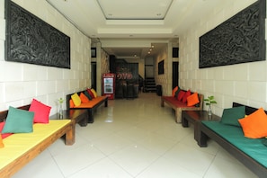 Um lobby de hotel com área de estar central, um refrigerador de Coca-Cola e uma escadaria para um andar superior.