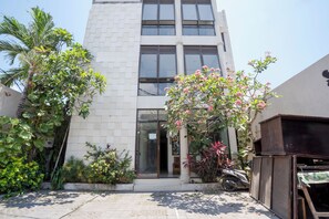 Um edifício moderno com fachada branca, janelas grandes e portão fechado.