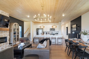 Una cocina moderna con una isla central, electrodomésticos integrados y un comedor con mesa y sillas de madera.