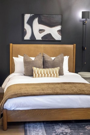 Un letto con testiera in legno, numerosi cuscini e una coperta decorata.