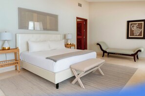 Ein Schlafzimmer mit einem großen Bett, Nachttischen, einer Bank und einer Tür.