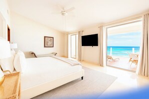 Een hotelkamer met een bed, een televisietoestel, een plafondventilator en uitzicht op de oceaan.
