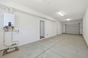 Eine saubere, leere Garage mit Warmwasserbereiter und geschlossener Garagentür.