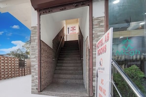 Entrada de hotel con una escalera que conduce a las habitaciones, un letrero que indica casa de huéspedes y el logotipo de Mcgh.