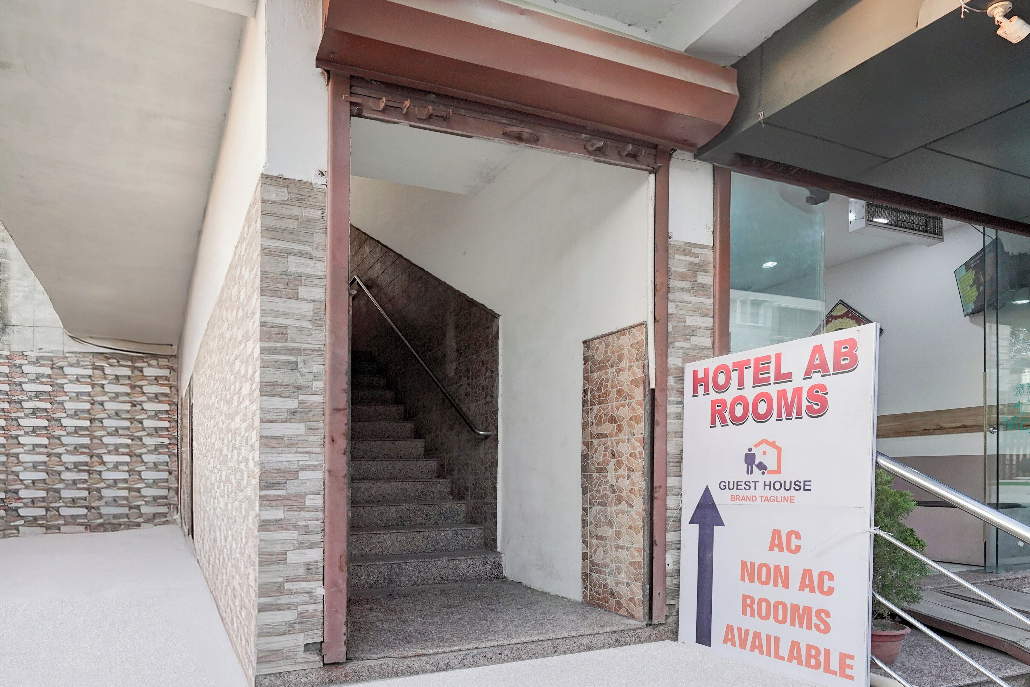 A hotel entrance with a sign indicating 'HOTEL AB ROOMS' and 'AC NON AC ROOMS AVAILABLE'.