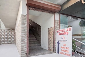 Entrada de un hotel con un cartel que indica 'HOTEL AB ROOMS' y 'HABITACIONES CON Y SIN AIRE ACONDICIONADO DISPONIBLES'.