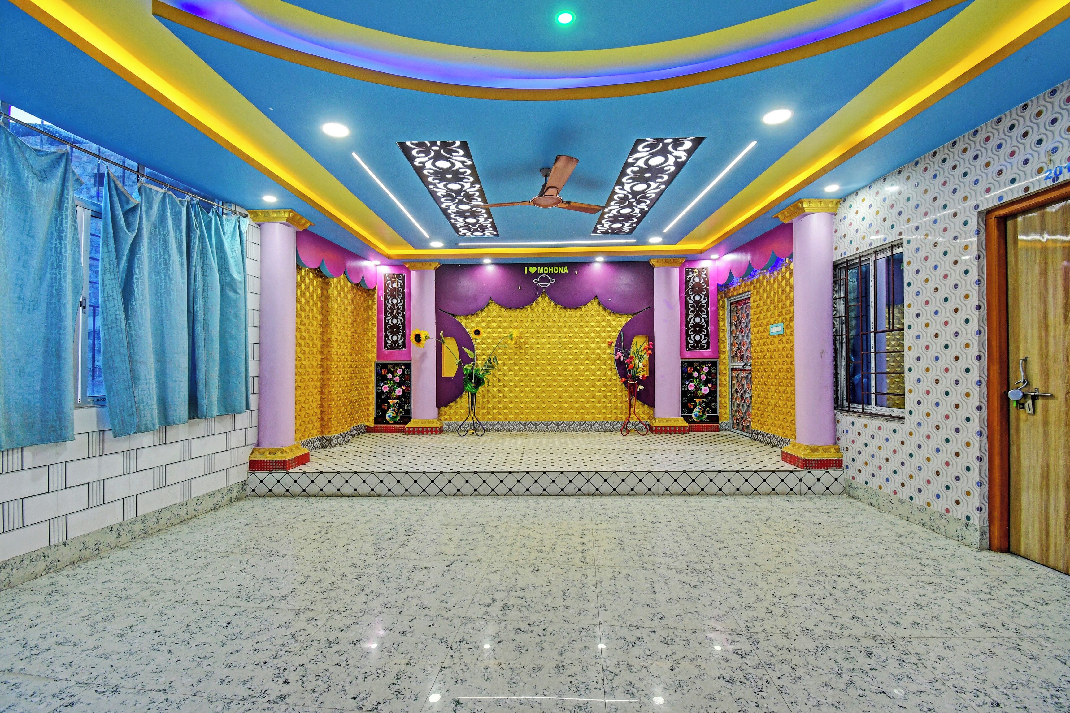 A room with a patterned floor, a ceiling with decorative lighting, and a floral arrangement.