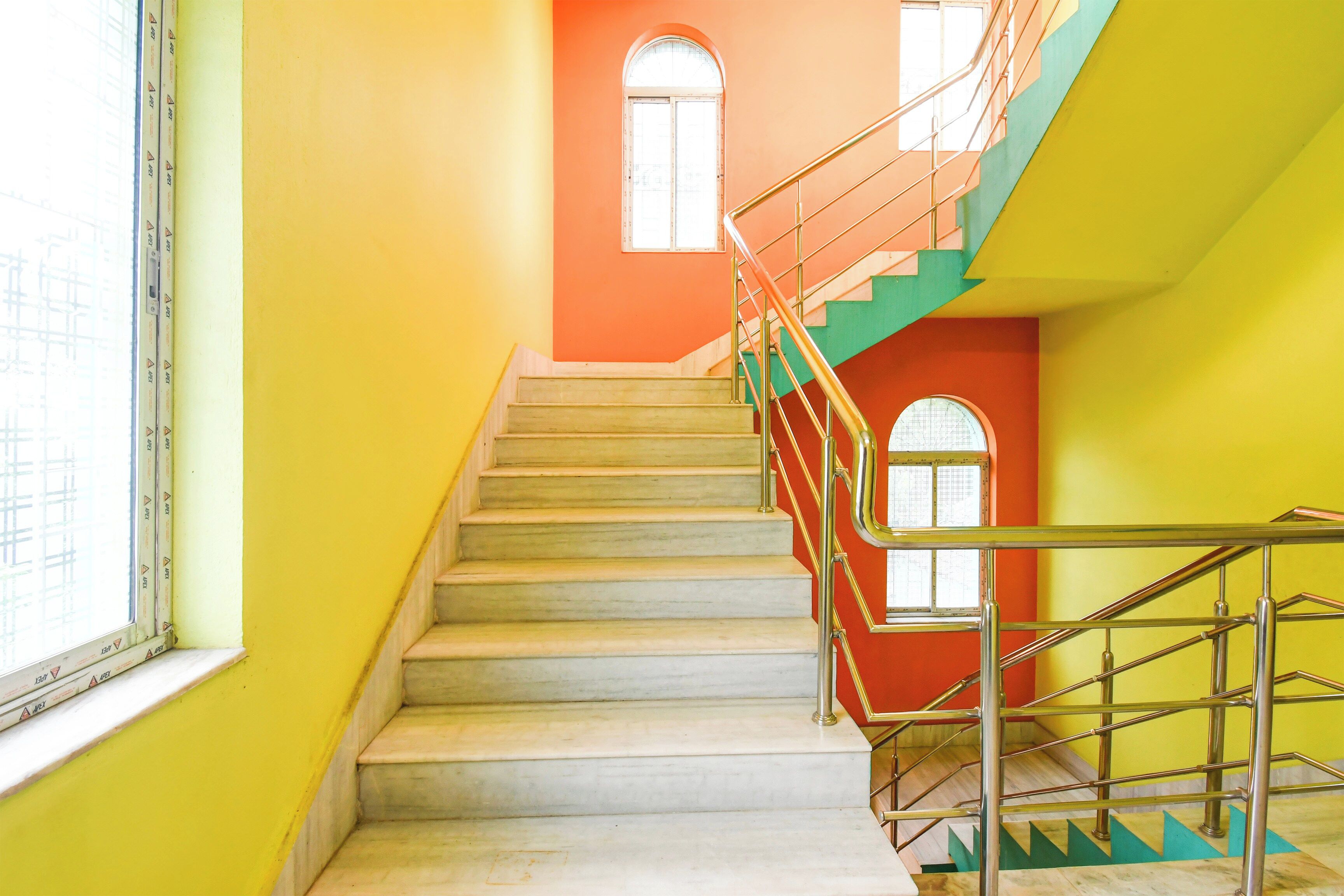 A staircase with a handrail, a window, and a door with a geometric design.