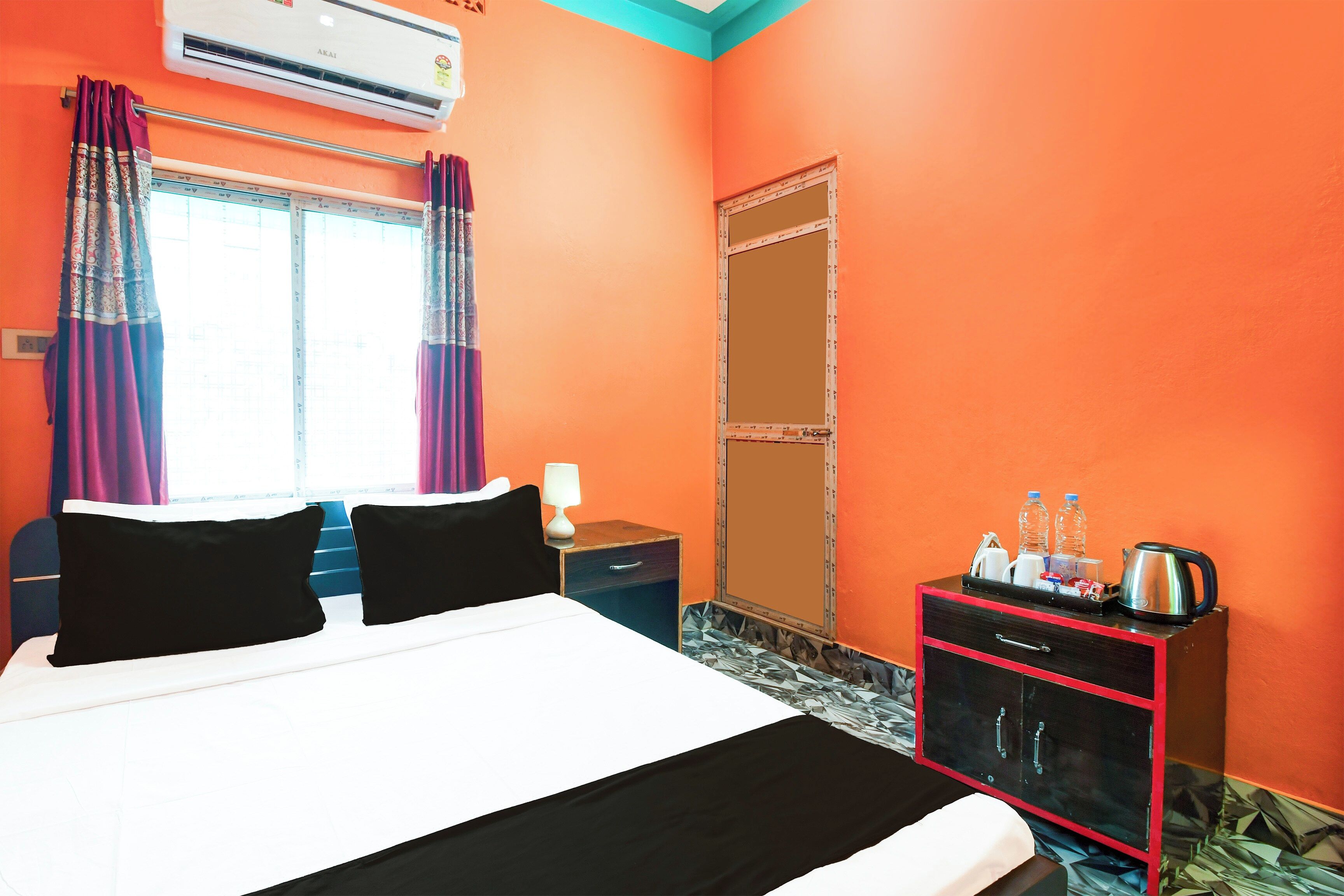 A hotel room with a bed, a nightstand, a wardrobe, and a window with curtains.