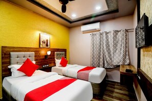 A hotel room with two beds, a ceiling fan, an air conditioning unit, a television, and a patterned curtain. - Hotel O Padma Manor (Behrampur)