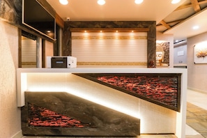 A reception desk with a modern design, a digital display, and a decorative wall with a Buddha statue. - Hotel O Padma Manor (Behrampur)