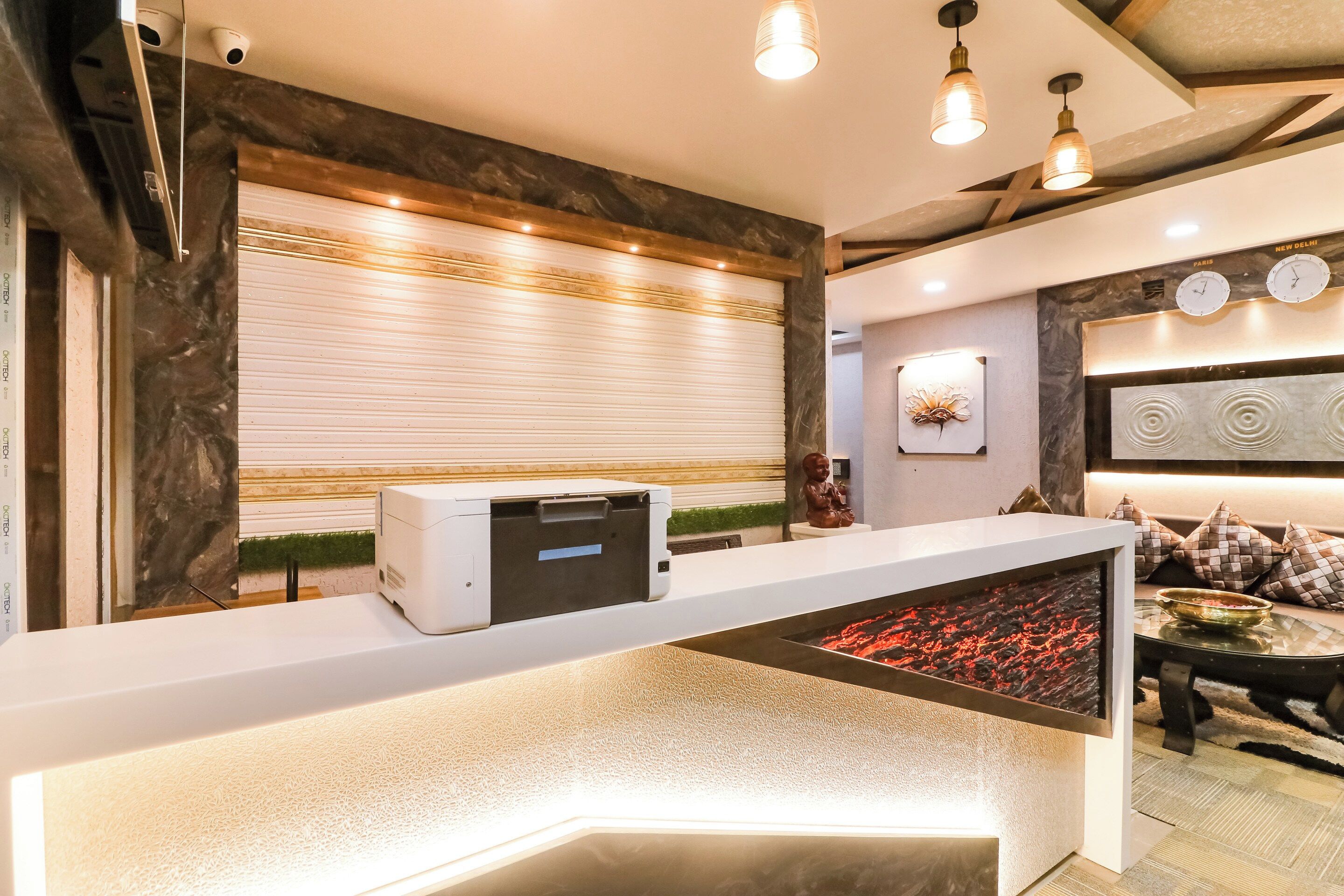 A reception desk with a printer, a wall clock, and a decorative wall with a leaf pattern.