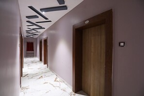 Un pasillo con suelo de mármol, puertas de madera y techo con diseños geométricos.