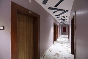 Un pasillo con puertas de madera y un suelo de mármol blanco.