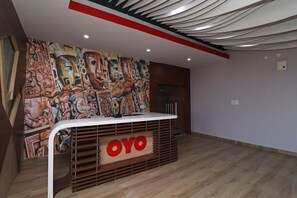 A reception desk with a modern design, a large mural on the wall, and a wooden floor. - Hotel O Nirmalya Plaza (Behrampur)