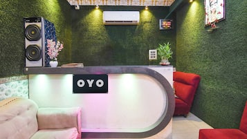 Un espace d’accueil avec une enseigne indiquant « OYO », un haut-parleur, une plante en pot et une chaise rouge.