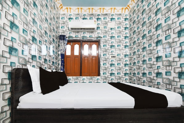 Un dormitorio con una cama, un ventanal y una pared con diseño geométrico.