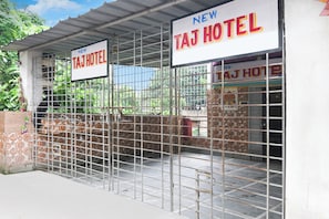 Entrada de un hotel con una reja metálica y un letrero que dice 'NEW TAJ HOTEL'.
